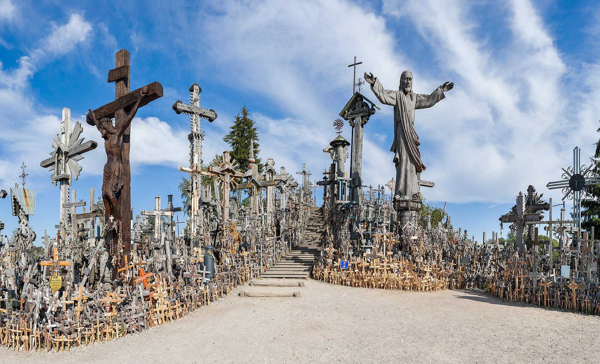 A small hill crowded with thousands of wooden and metal crosses under a blue sky