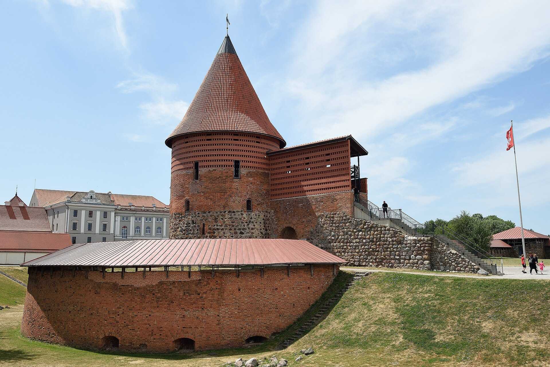 Round red brick castle tower with a pointed roof