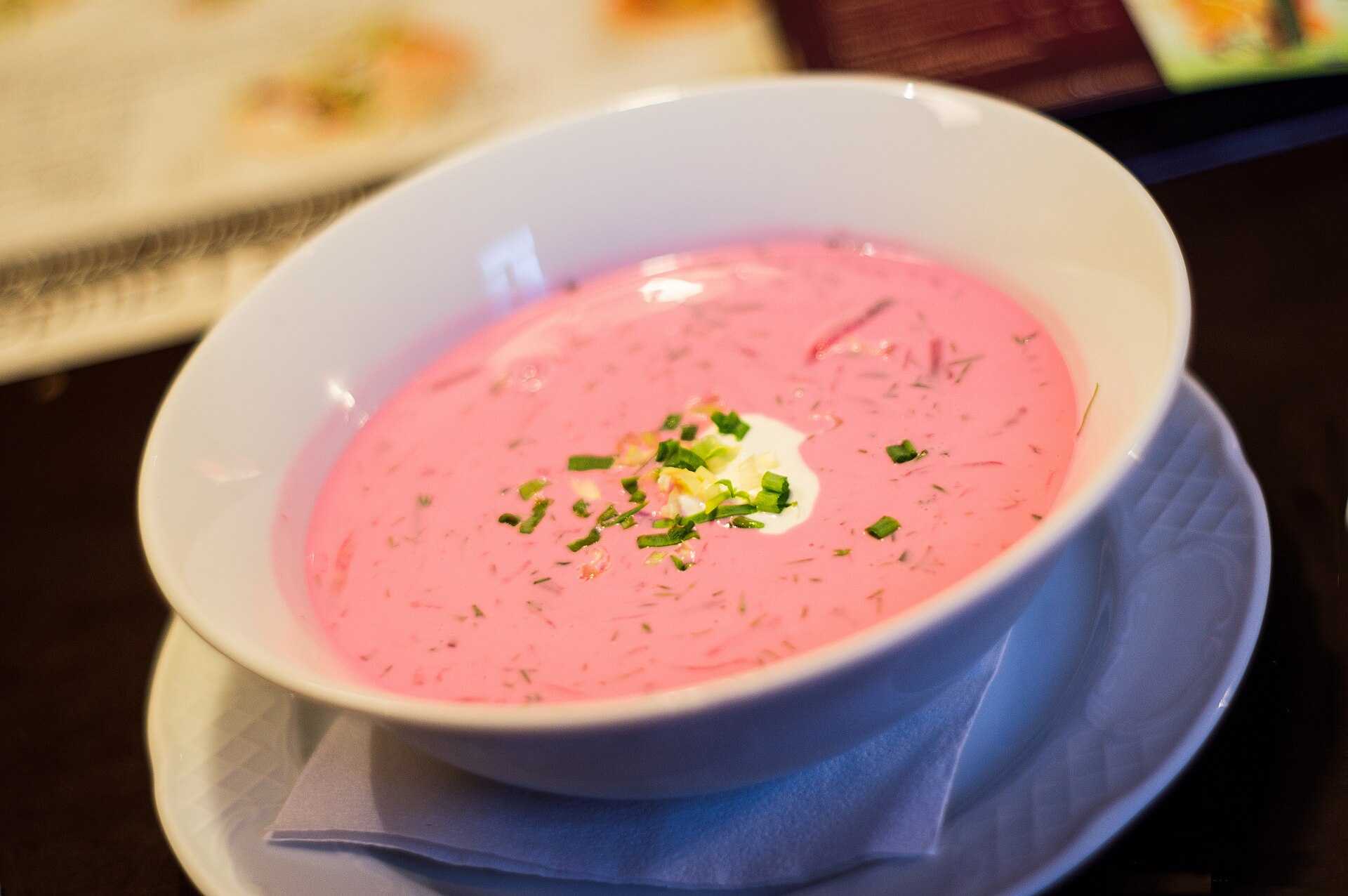 A bowl of bright pink cold beet soup with egg and dill