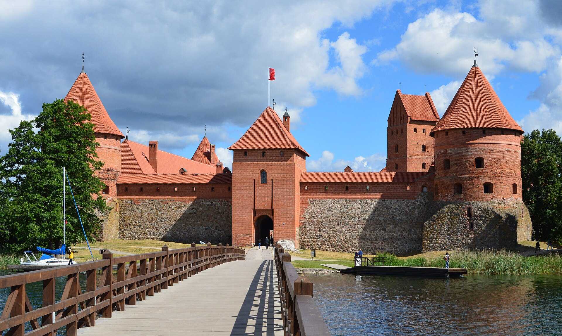 Red brick castle with towers on an island, reflected in a lake